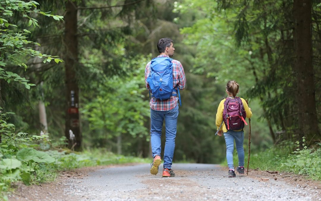 man in blue jacket and blue denim jeans walking on dirt road during daytime