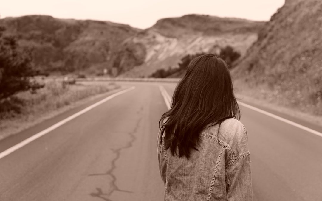 woman in gray denim jacket standing on road during daytime