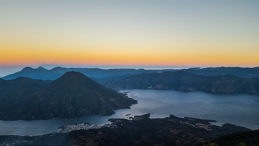 aerial photo of body of water beside mountain during daytime