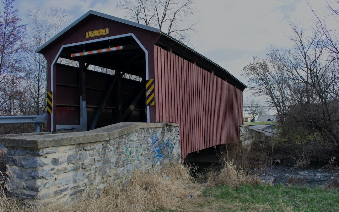 a covered bridge over a small stream in a rural area