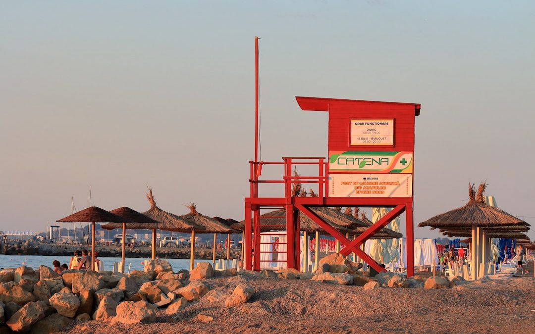 a red lifeguard tower sitting on top of a sandy beach