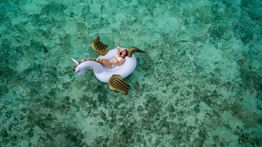 woman wearing white bikini set lying on white and brown unicorn inflatable float