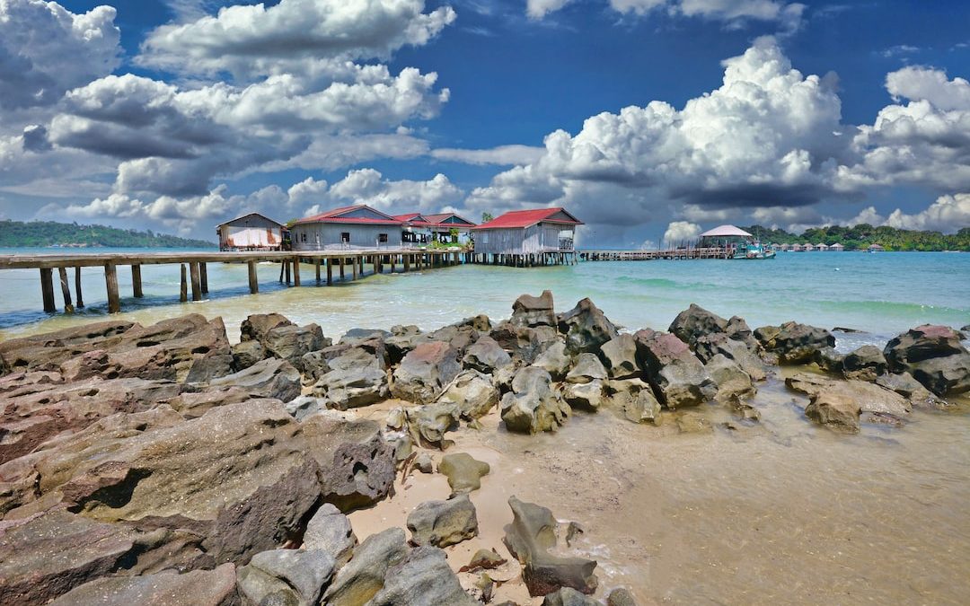 a rocky beach with a pier and buildings in the background