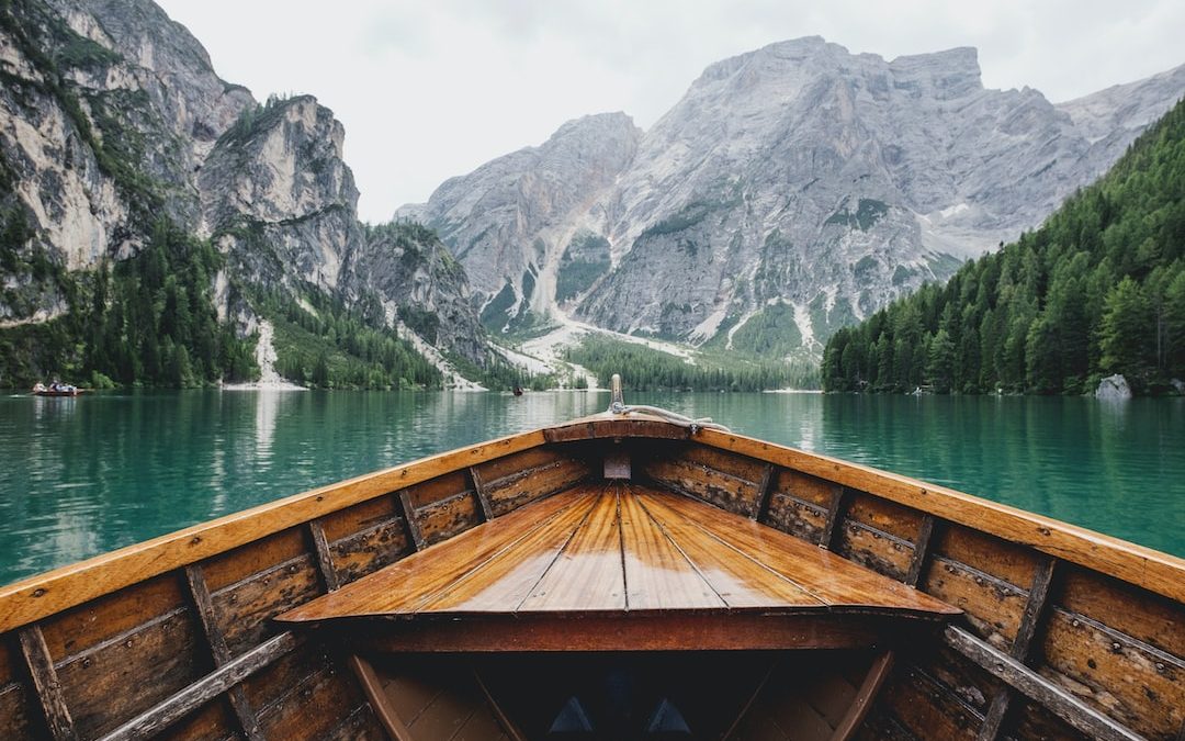 brown wooden boat moving towards the mountain