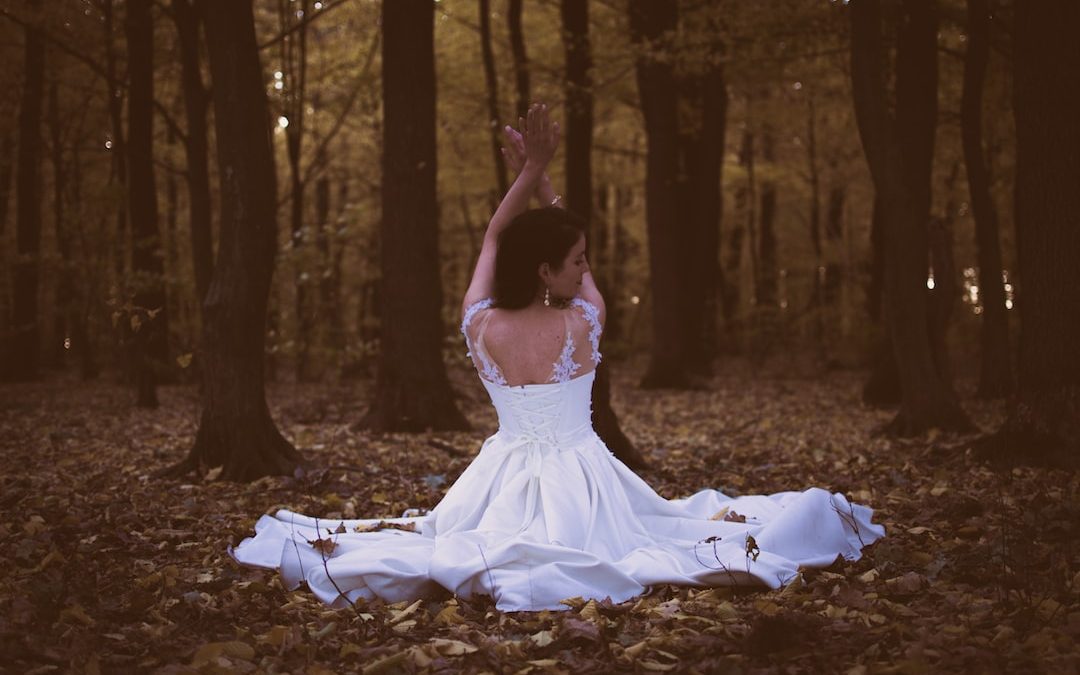 woman in white sleeveless dress sitting on piles of leaves