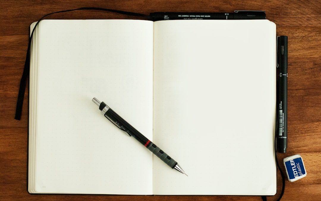 black and silver retractable pen on blank book