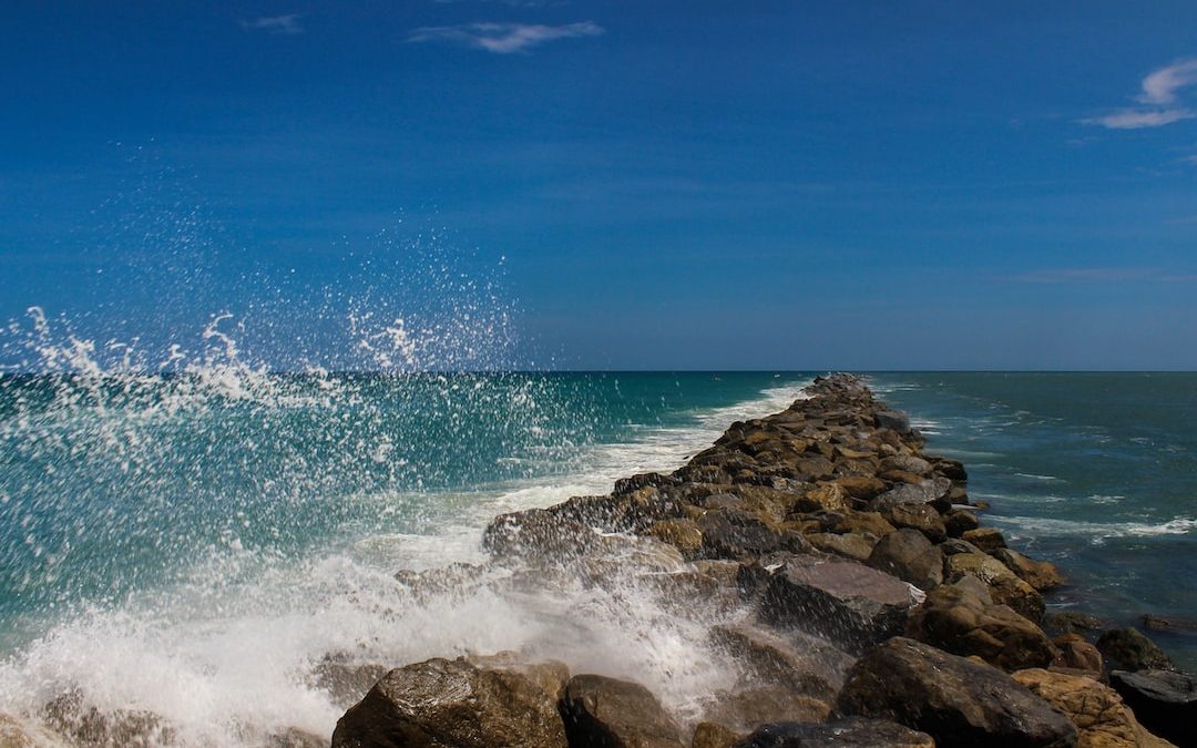 ocean waves crashing on rocks under blue sky during daytime