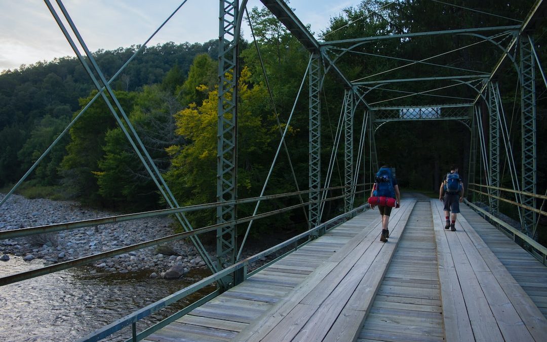 two people walking across a bridge over a river