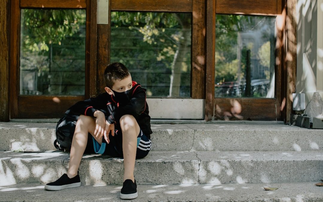 boy in black t-shirt and blue denim jeans sitting on concrete bench