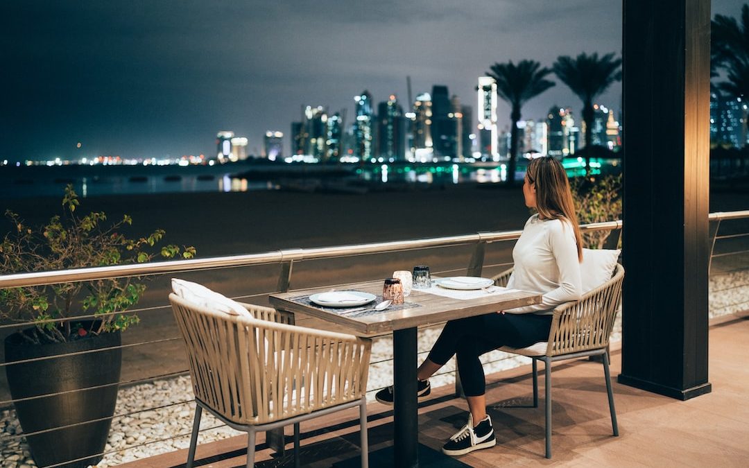 a woman sitting at a table with a view of a city