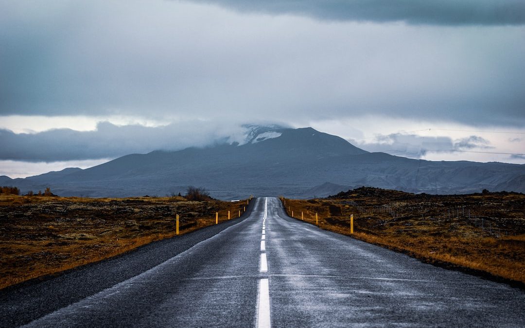 gray concrete road near mountain under white sky during daytime