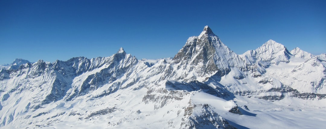 a mountain range covered in snow under a blue sky