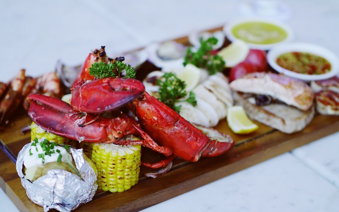 cooked lobsters on brown wooden serving tray with sauce