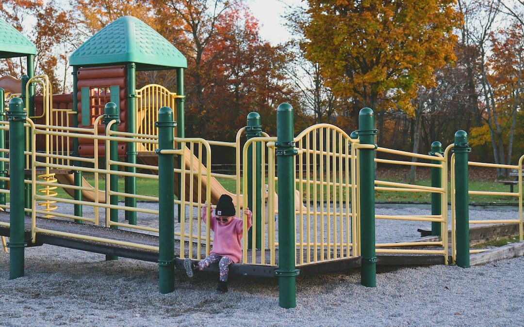 a little girl playing on a yellow and green playground