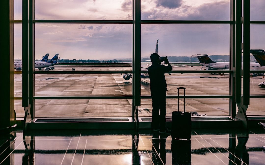 silhouette of person standing in front of glass while taking photo of plane