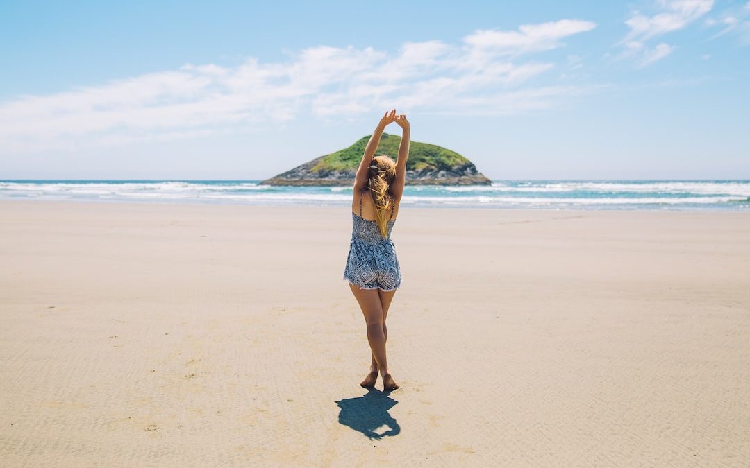 woman on seashore near island under blue sky