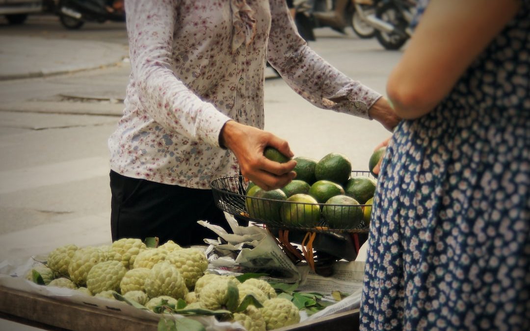 a woman standing next to a table filled with fruits and vegetables