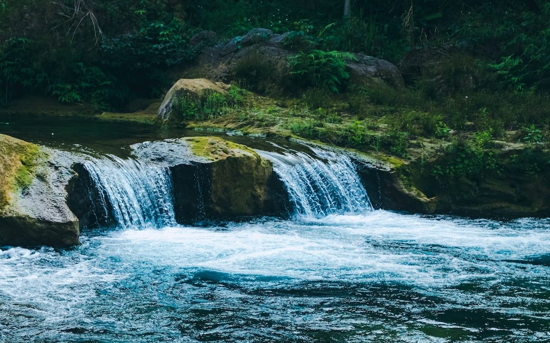 a man standing on a rock next to a waterfall