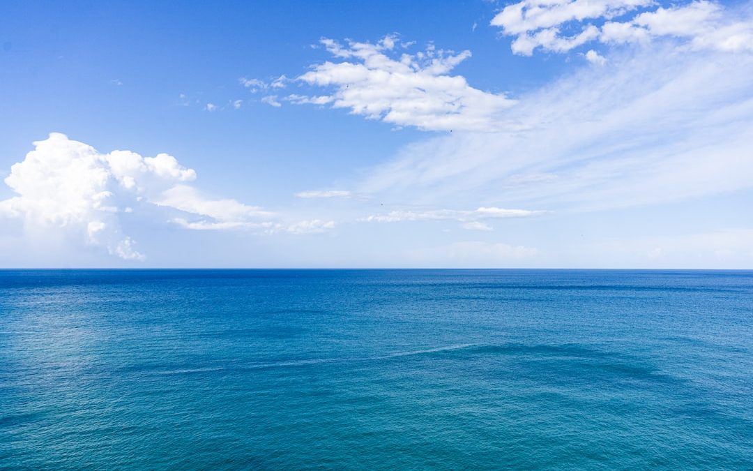 blue sea under blue sky and white clouds during daytime