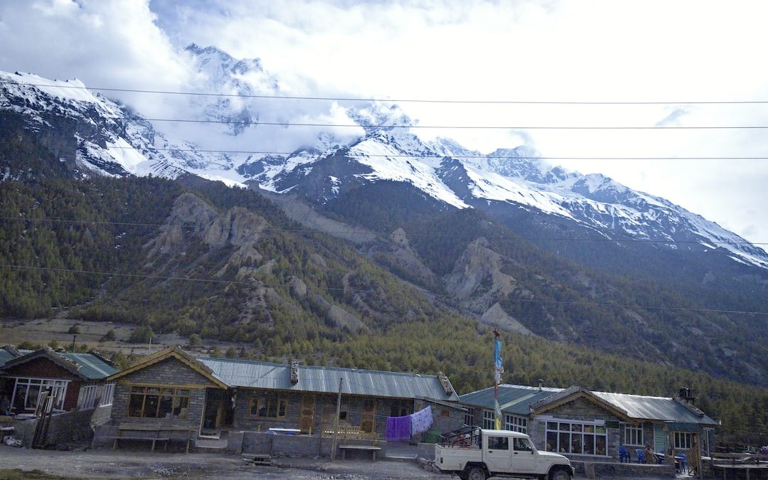 a truck parked in front of a building with mountains in the background