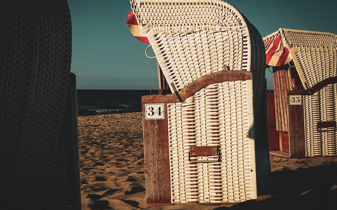 a couple of chairs sitting on top of a sandy beach