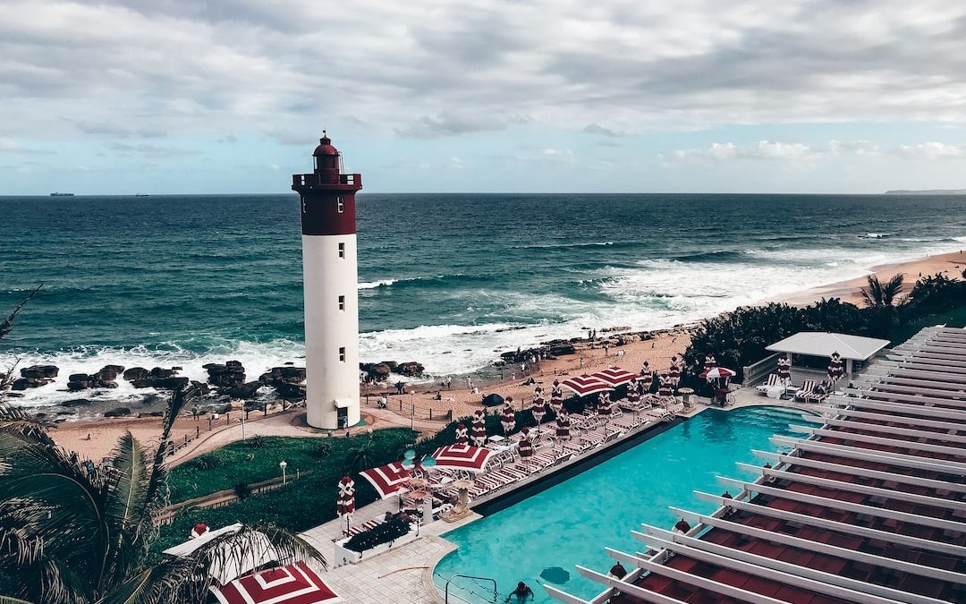 white and red lighthouse near body of water during daytime