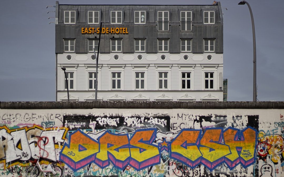 a wall covered in graffiti next to a tall building