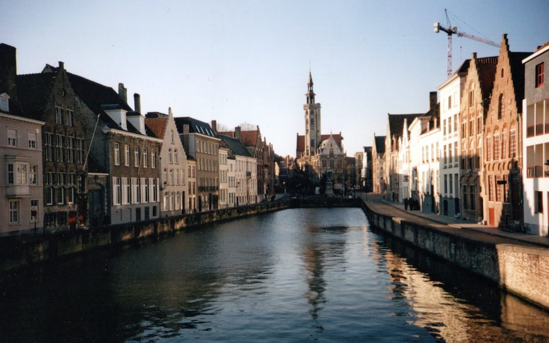 river between concrete buildings under white sky during daytime