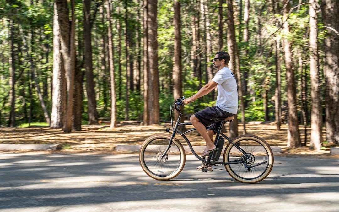 man in white t-shirt riding on bicycle in the middle of the road during daytime