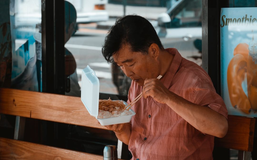 man sitting on brown wooden bench while eating