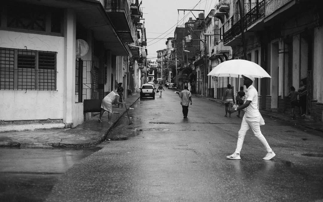 man holding umbrella walking on gray road