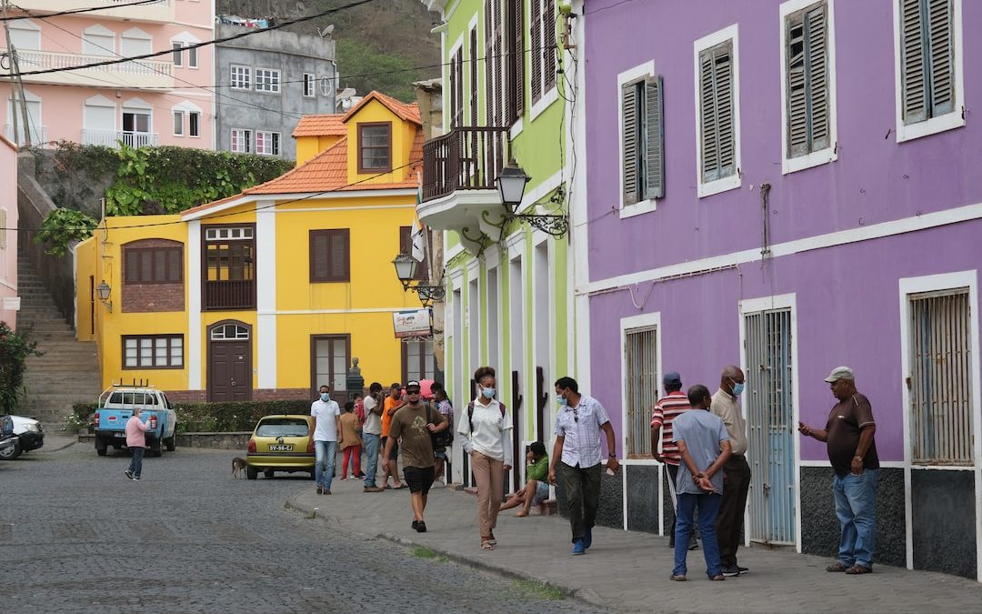 a group of people walking down a street next to colorful buildings