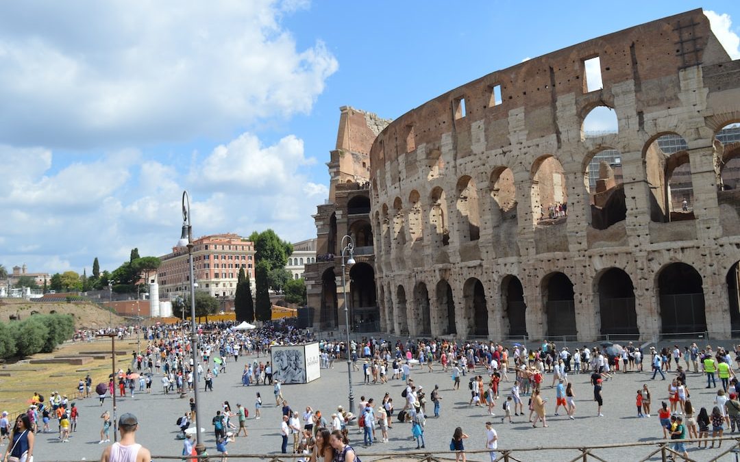 a large stone building with many arches and people walking around