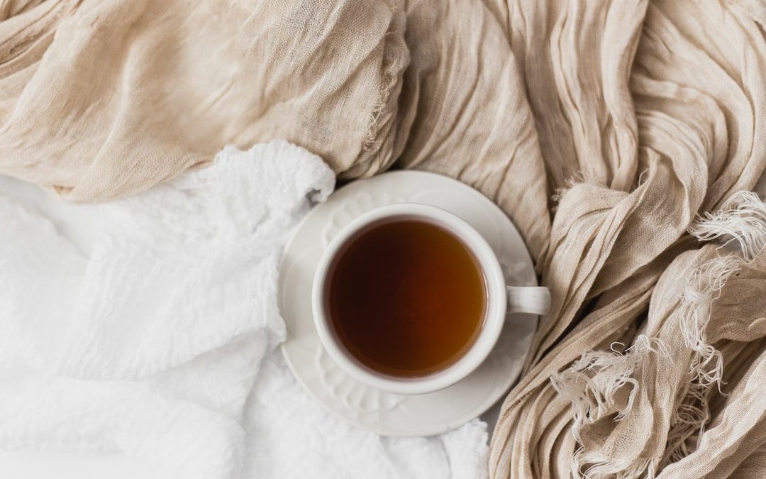 tea filled white ceramic mug on white ceramic saucer