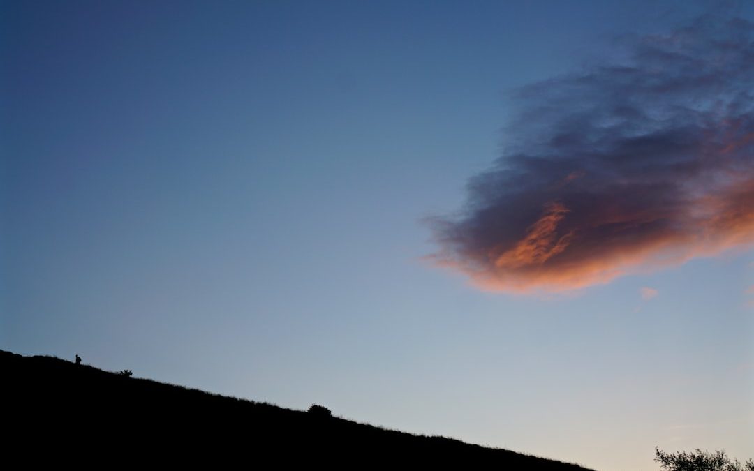 silhouette of mountain slope under cloudy sky