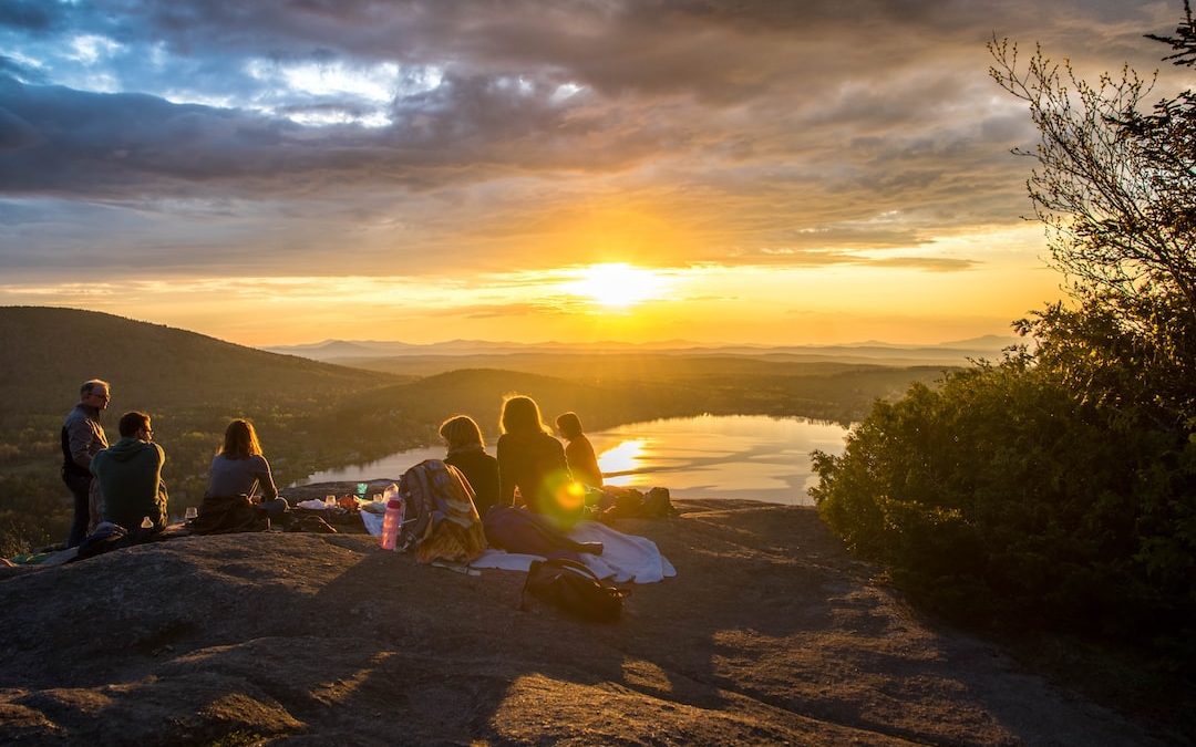 group of people sirring under sunset