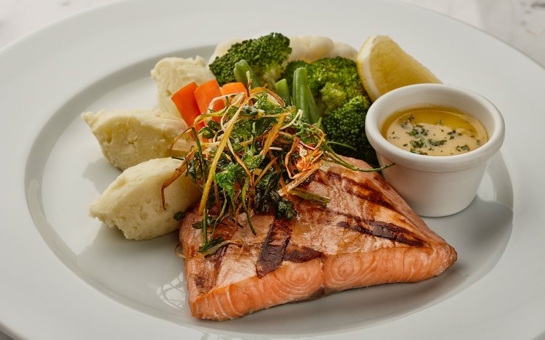 a white plate topped with fish and vegetables