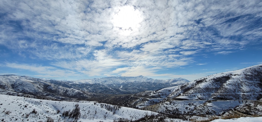snow covered mountains under blue sky and white clouds during daytime