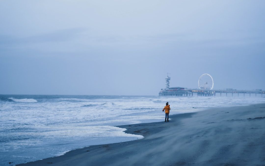 person wearin yellow jacket walking on seashore