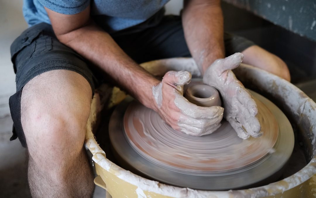 person making clay pot on the floor