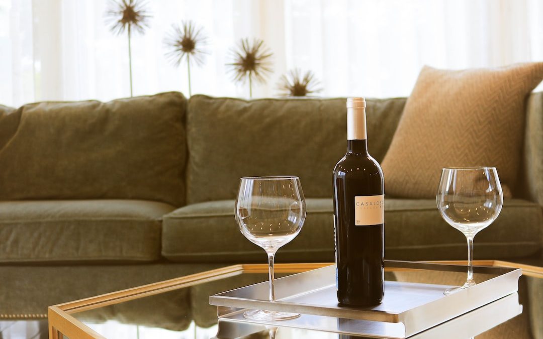 black wine bottle beside two wine glasses