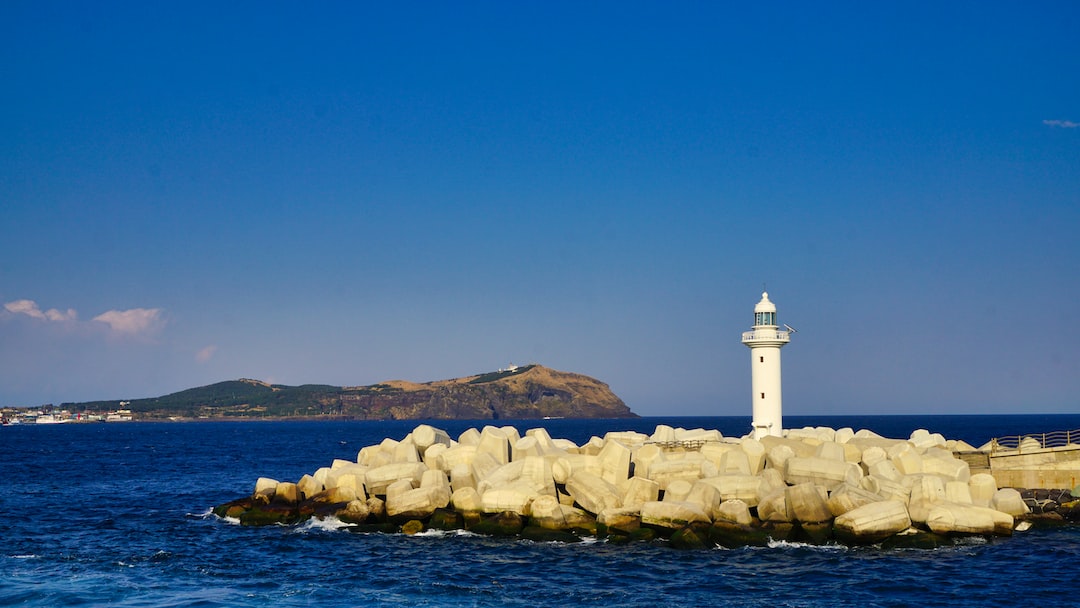 white lighthouse on rocky shore during daytime