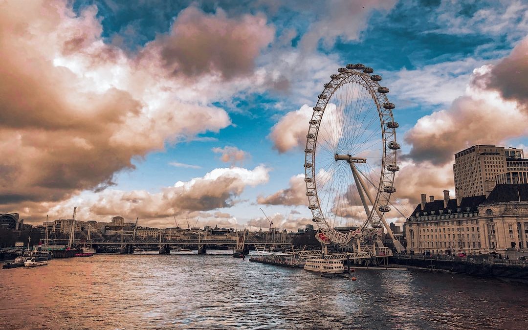 ferris wheel beside body of water under cloudy sky during daytime