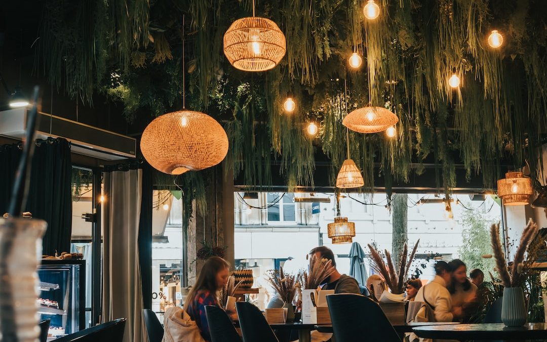 a group of people sitting at tables under lanterns