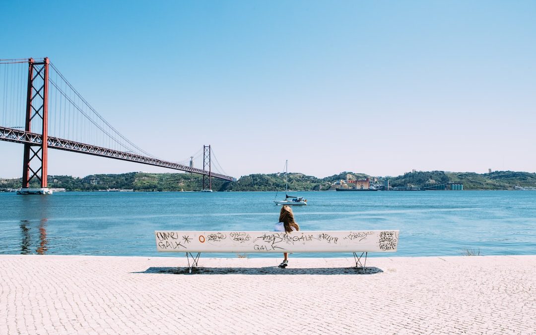 woman sitting on white bench in front of sea