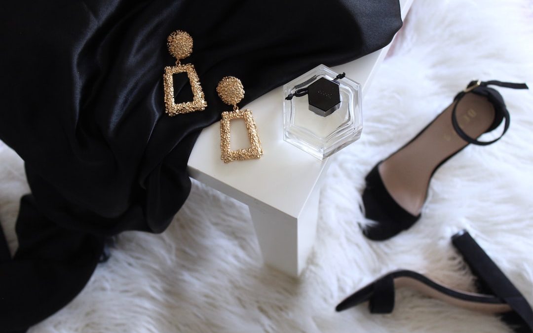 pair of gold-colored earrings on table and black ankle-strap pumps on area rug