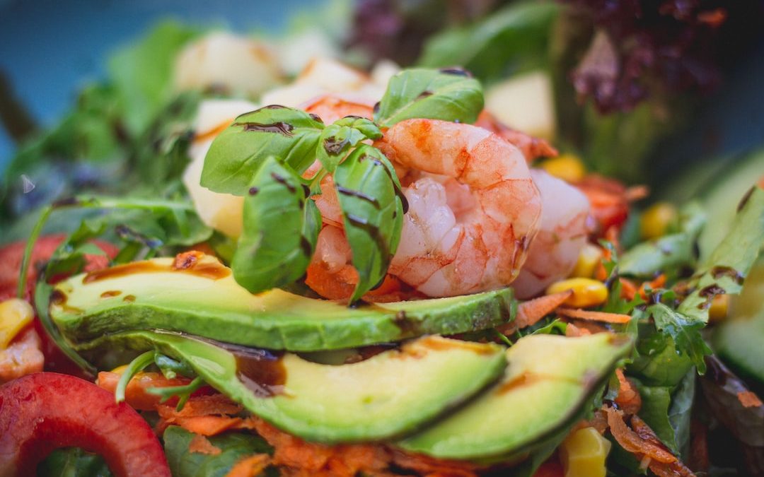 a salad with shrimp, avocado, carrots, and lettuce