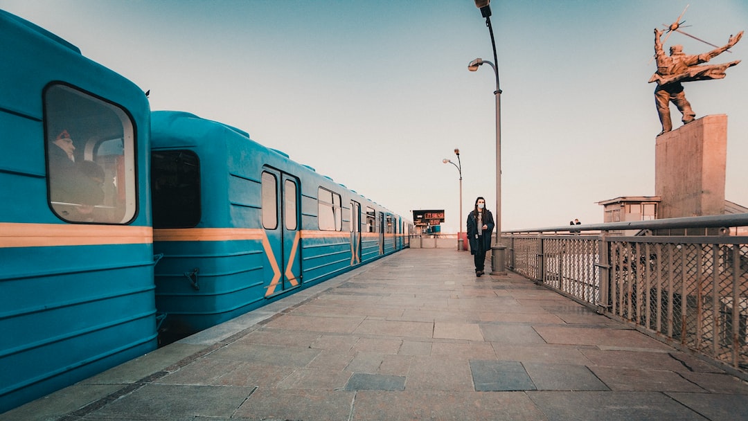 person walking near blue train during daytime