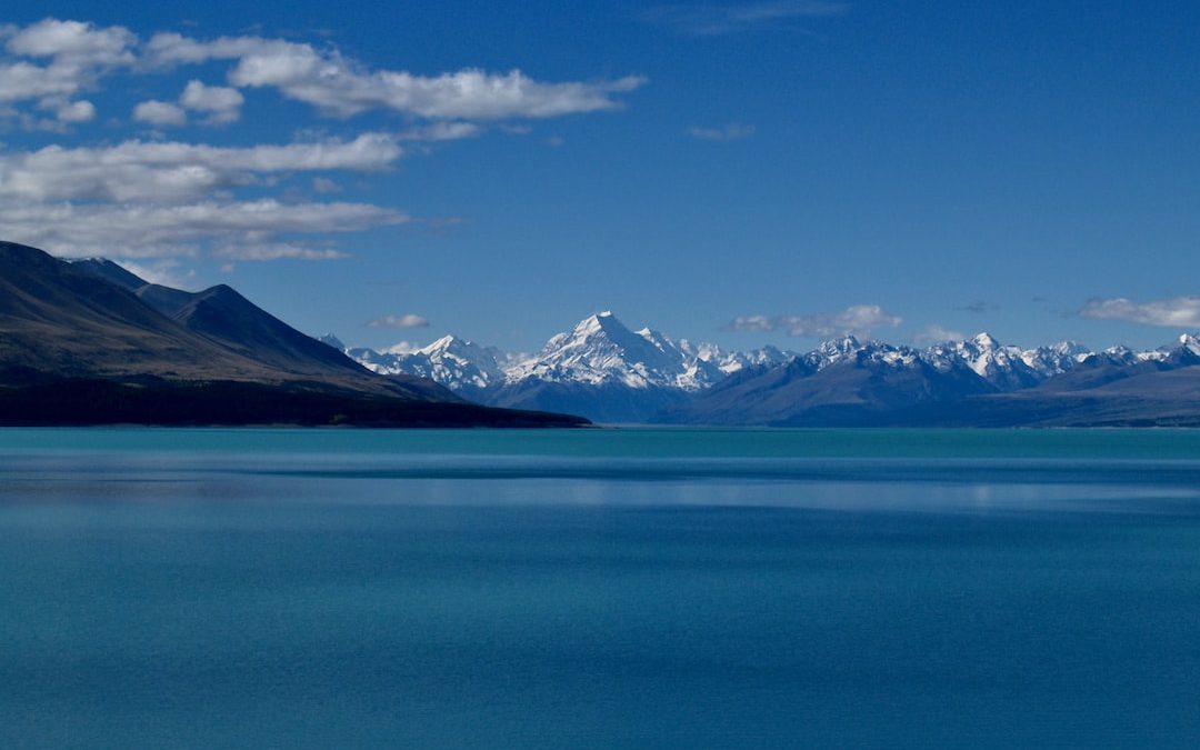 blue body of water near mountain under blue sky during daytime