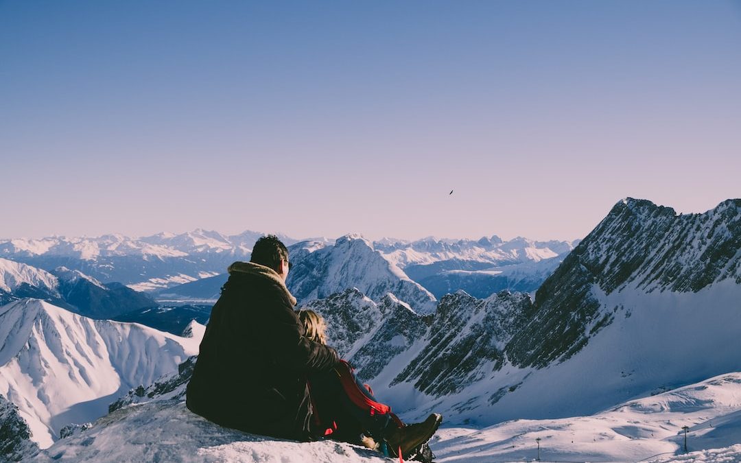 man and woman on top of peak